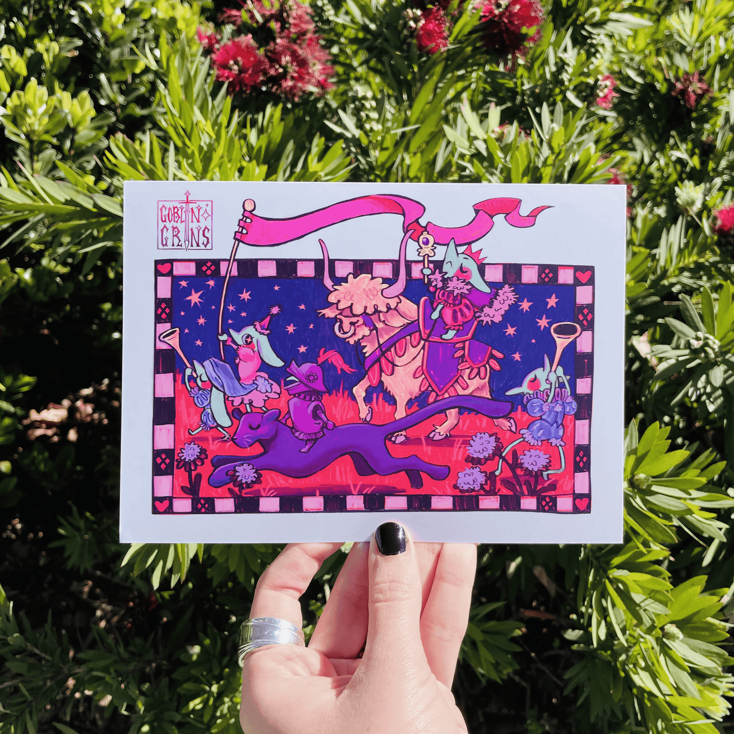 Colorful illustration of goblins and animals held up against a green leafy background