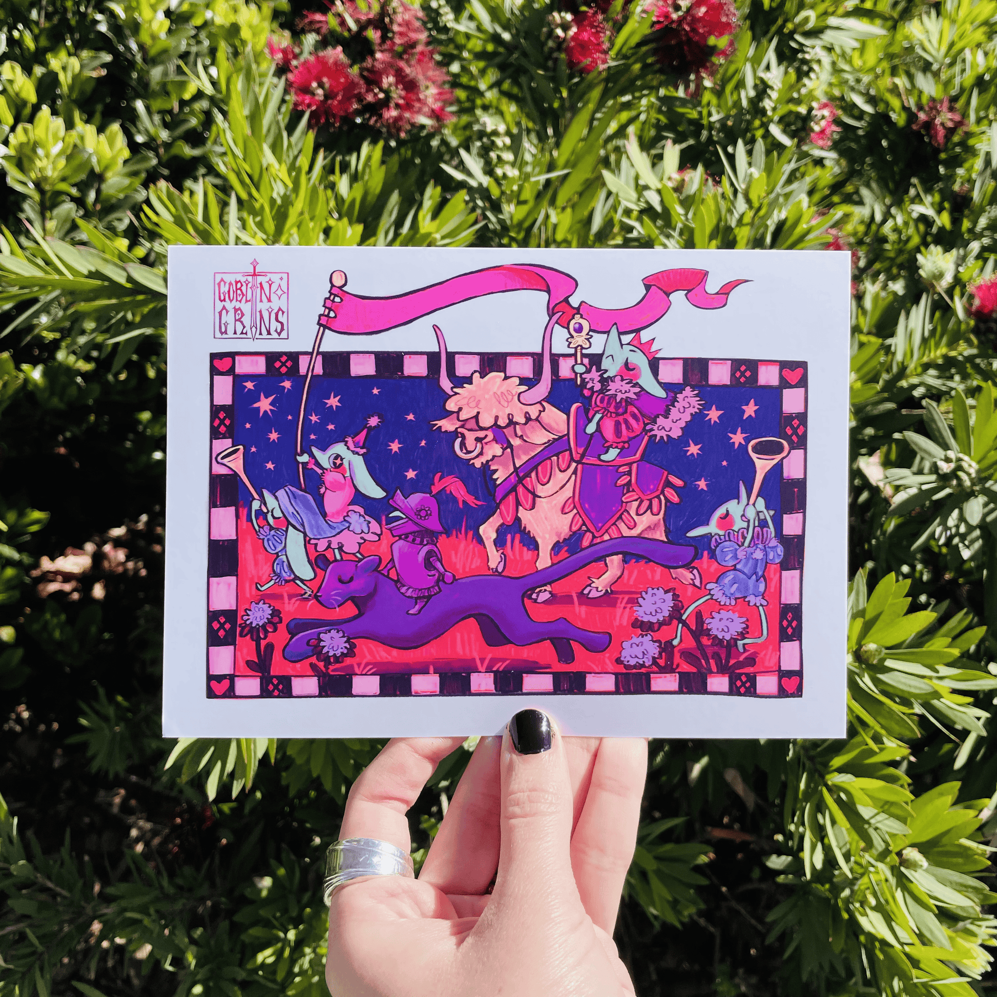 Colorful illustration of goblins and animals held up against a green leafy background